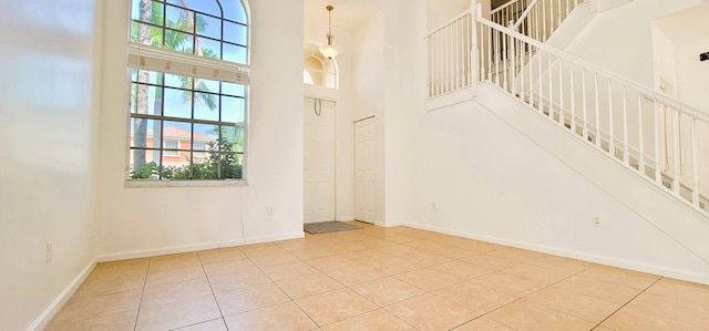 interior space featuring a towering ceiling, a healthy amount of sunlight, and light tile floors