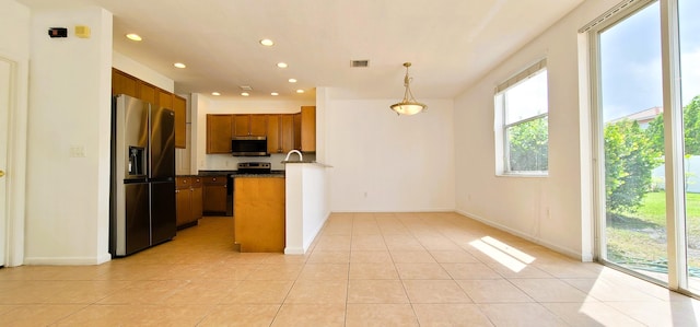 kitchen with appliances with stainless steel finishes, a wealth of natural light, light tile floors, and pendant lighting