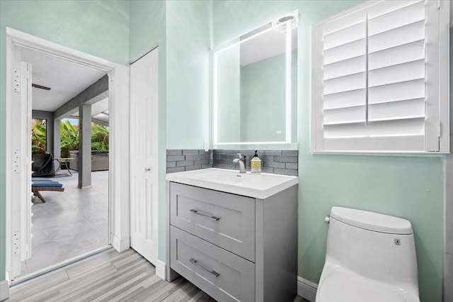 bathroom with tile flooring, backsplash, toilet, and large vanity