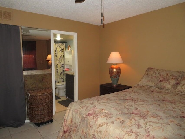 bedroom with tile flooring, ensuite bathroom, ceiling fan, and a textured ceiling