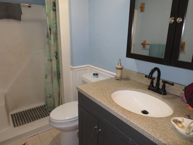 bathroom with curtained shower, tile flooring, toilet, and vanity