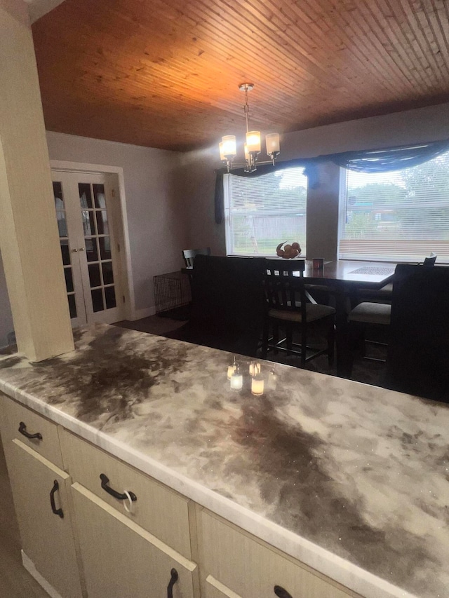 kitchen featuring cream cabinetry, decorative light fixtures, wood ceiling, and an inviting chandelier