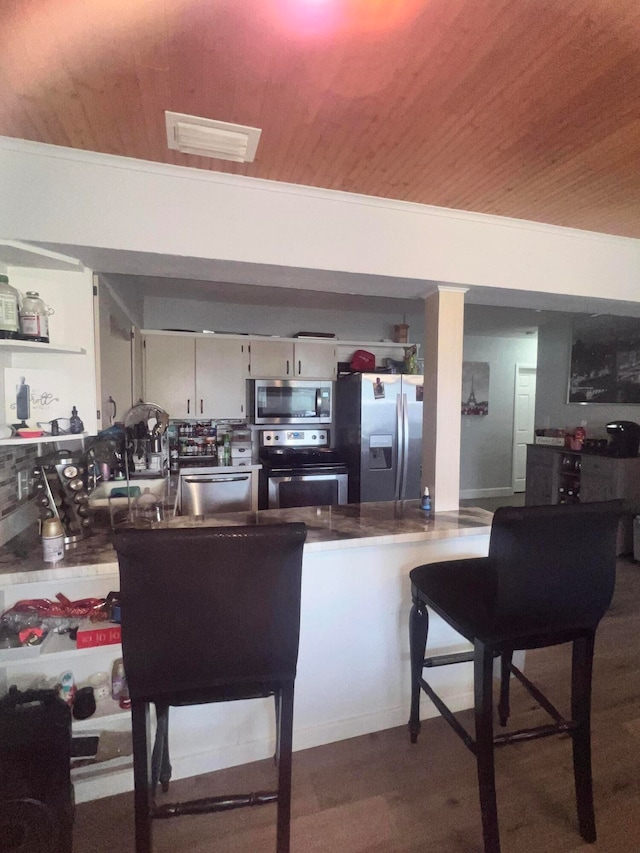 kitchen featuring white cabinetry, wood-type flooring, wooden ceiling, and stainless steel appliances