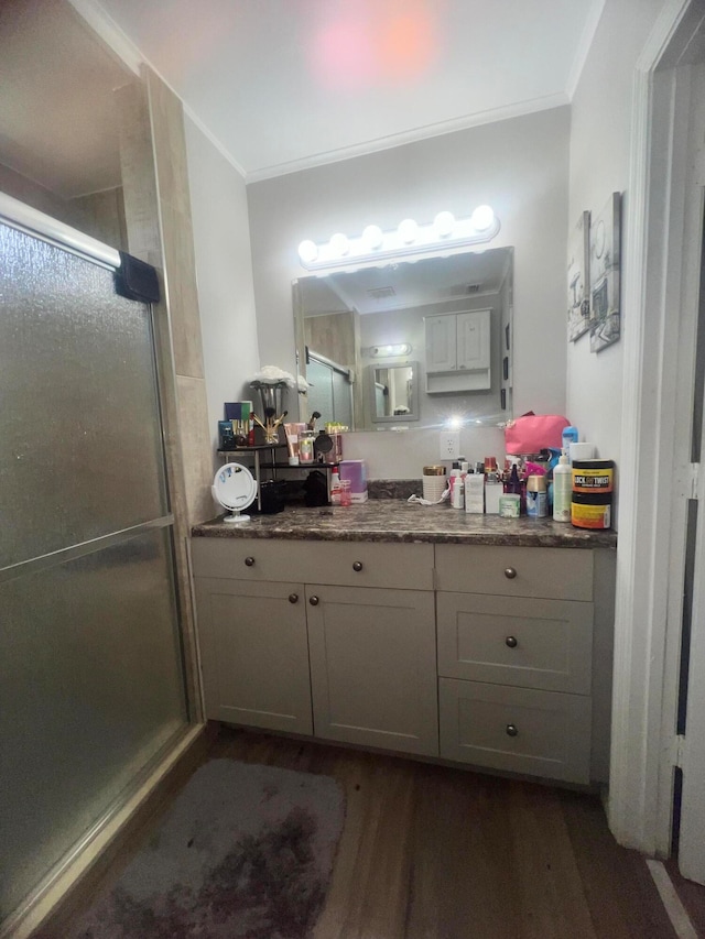 bathroom with walk in shower, wood-type flooring, crown molding, and vanity