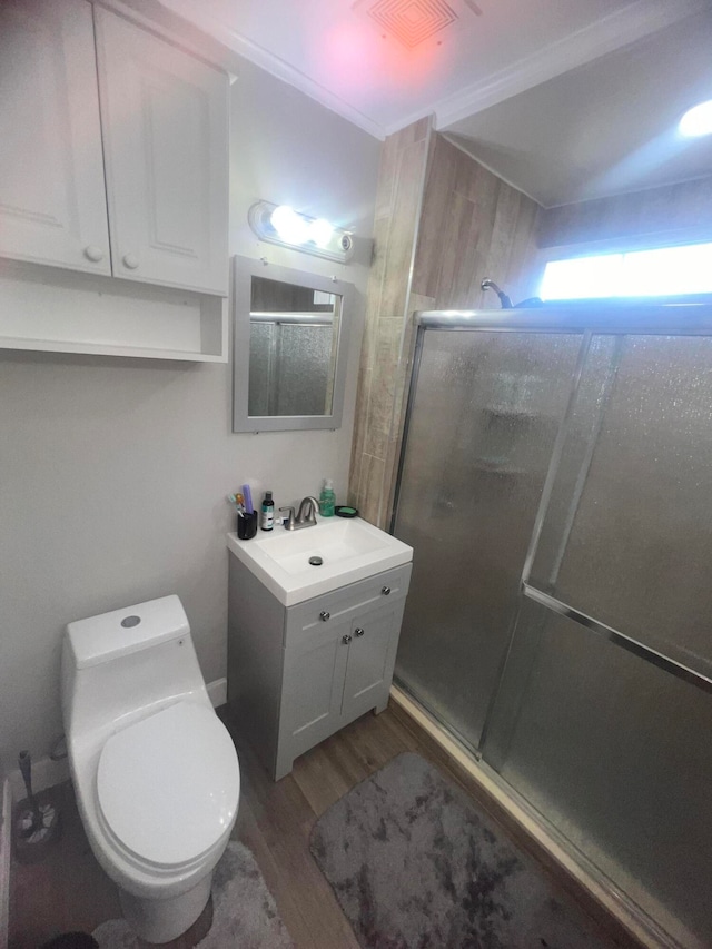 bathroom featuring vanity, hardwood / wood-style flooring, toilet, and a shower with shower door