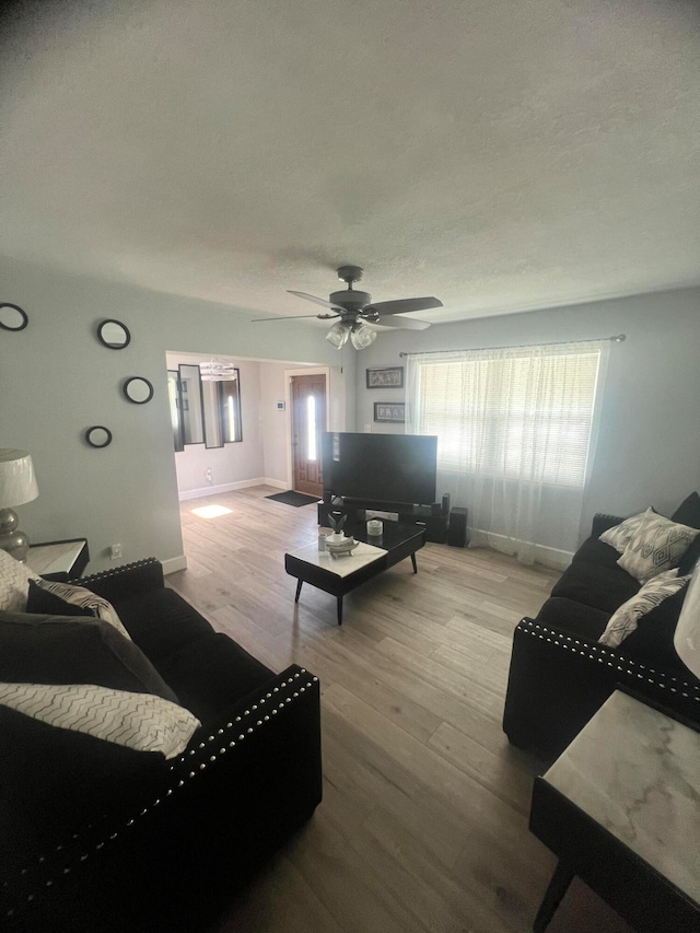 living room with a textured ceiling, light hardwood / wood-style floors, and ceiling fan