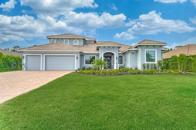 mediterranean / spanish home featuring a tile roof, an attached garage, decorative driveway, a front lawn, and stucco siding