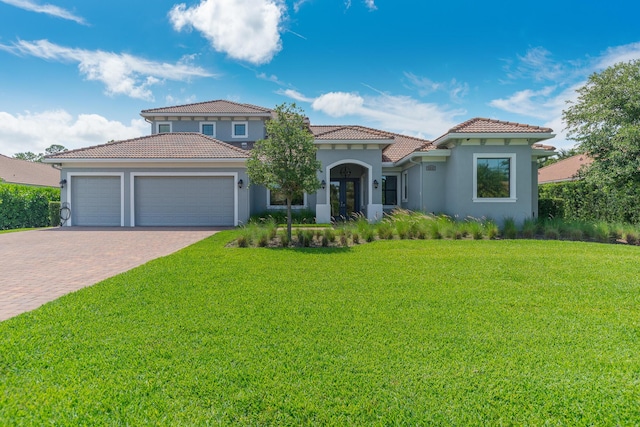 mediterranean / spanish-style house featuring french doors, a garage, and a front lawn