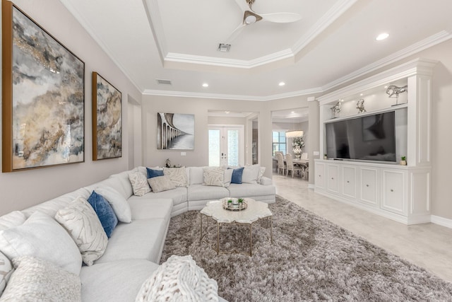 living area with ceiling fan, ornamental molding, a raised ceiling, and visible vents