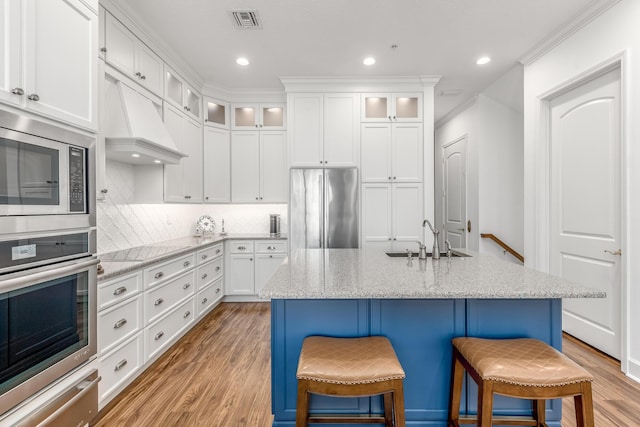 kitchen featuring white cabinets, sink, an island with sink, and appliances with stainless steel finishes