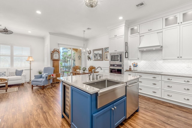 kitchen with white cabinetry, blue cabinets, premium range hood, and stainless steel appliances