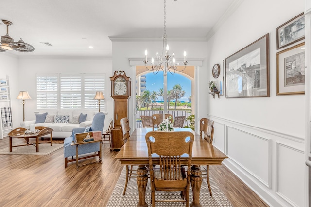 dining space featuring wood-type flooring, ceiling fan with notable chandelier, and ornamental molding