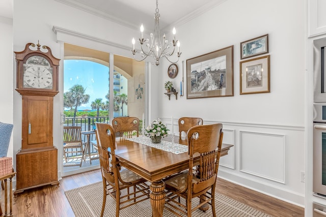 dining room featuring hardwood / wood-style floors, ornamental molding, and an inviting chandelier