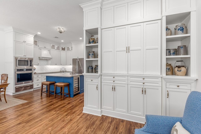 kitchen with white cabinetry, a kitchen breakfast bar, premium range hood, a kitchen island, and appliances with stainless steel finishes