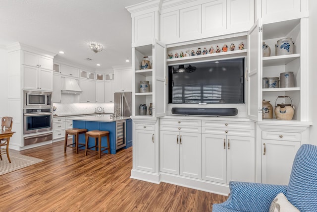 kitchen with appliances with stainless steel finishes, a breakfast bar, custom range hood, a kitchen island, and white cabinetry