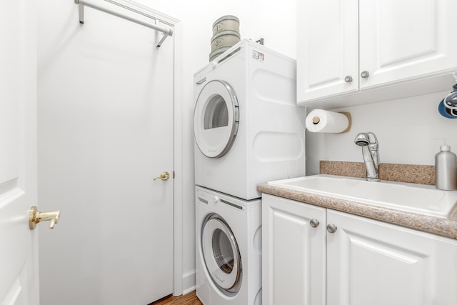 laundry area featuring stacked washer and dryer, cabinets, and sink