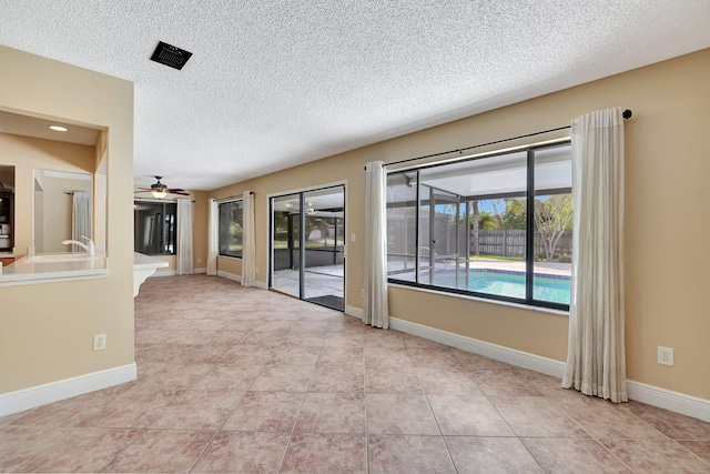 tiled empty room with sink, a textured ceiling, and ceiling fan