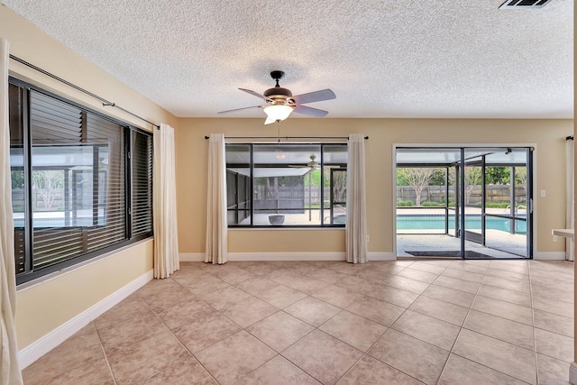 tiled spare room with a textured ceiling and ceiling fan