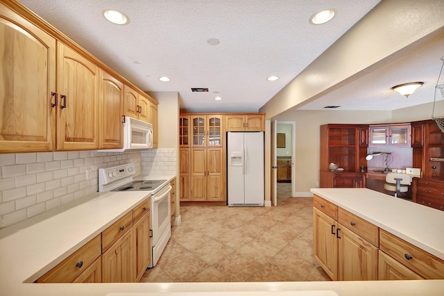 kitchen featuring a textured ceiling, backsplash, and white appliances