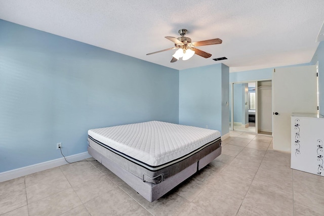 tiled bedroom with ceiling fan and a textured ceiling