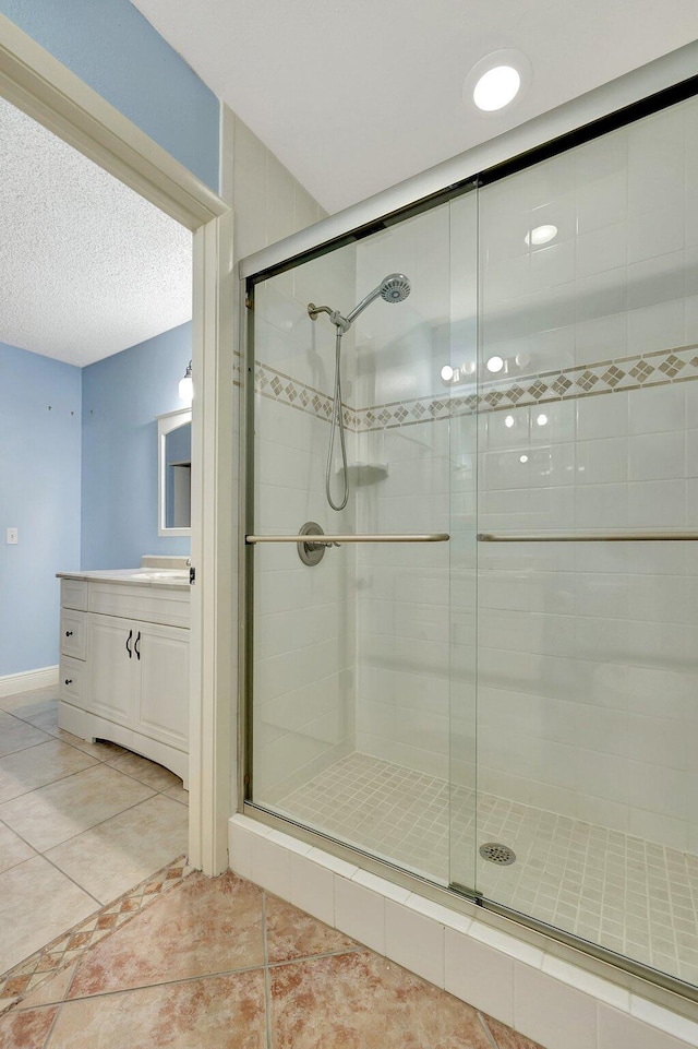 bathroom featuring vanity, a shower with shower door, and tile patterned floors