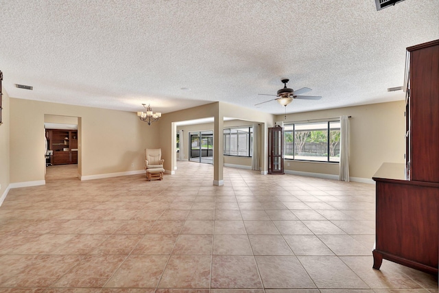 empty room with a textured ceiling, light tile patterned floors, and ceiling fan with notable chandelier