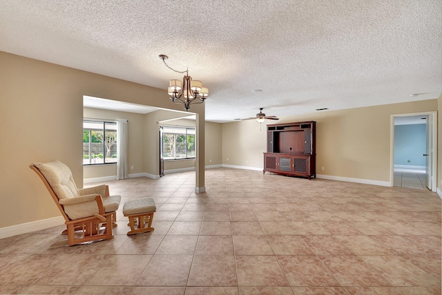 unfurnished room with a textured ceiling, light tile patterned flooring, and ceiling fan with notable chandelier