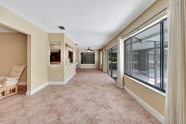 hall featuring light tile patterned flooring and a textured ceiling