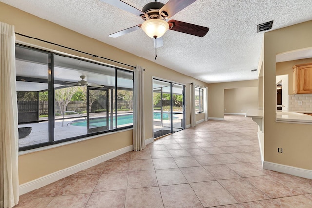 tiled spare room featuring a textured ceiling and ceiling fan