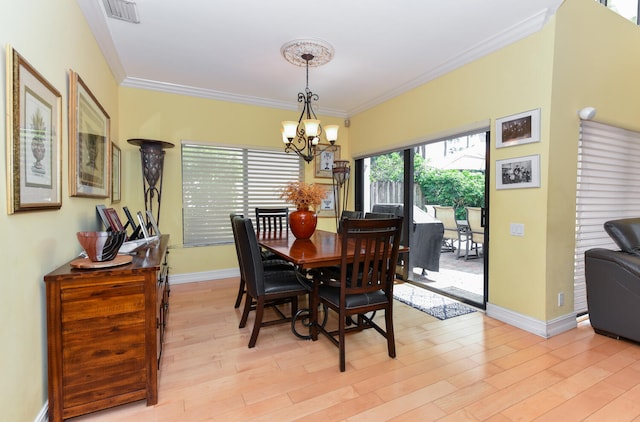 dining room featuring light wood-type flooring, ornamental molding, and a chandelier