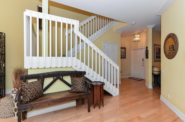 stairs featuring hardwood / wood-style floors, crown molding, and an inviting chandelier