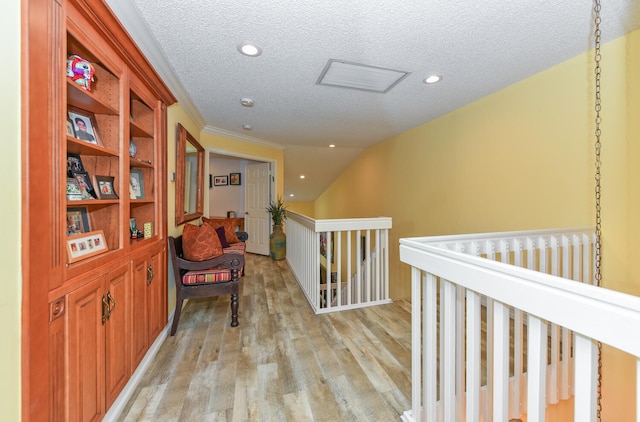 hallway featuring lofted ceiling, ornamental molding, a textured ceiling, and light hardwood / wood-style flooring