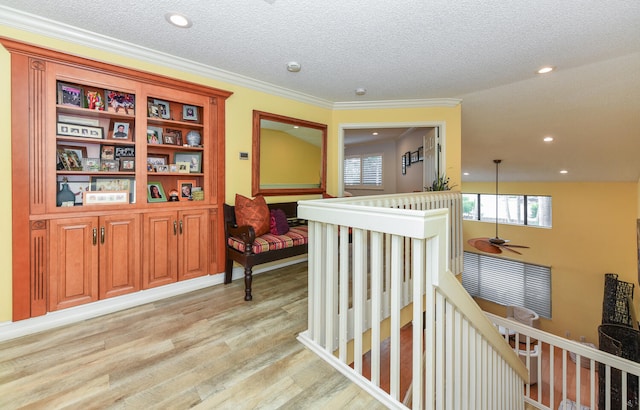 hallway with a textured ceiling, vaulted ceiling, crown molding, and light hardwood / wood-style flooring