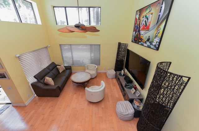 living room featuring light wood-type flooring, ceiling fan, and a healthy amount of sunlight