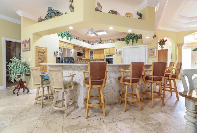 bar featuring ceiling fan, stainless steel appliances, and ornamental molding