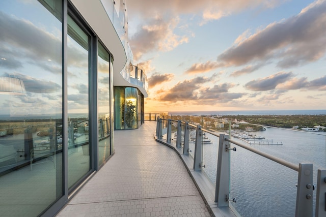 balcony at dusk featuring a water view