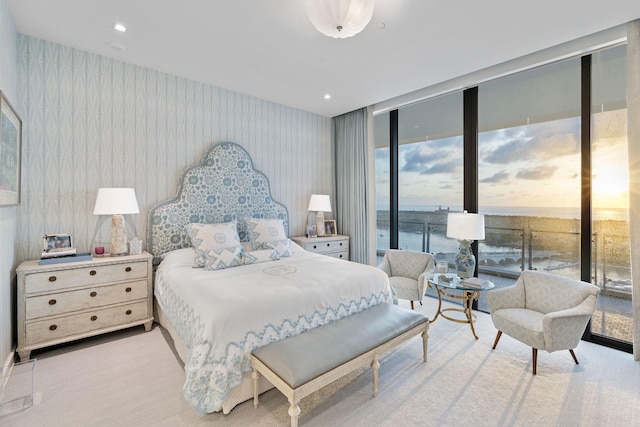 carpeted bedroom featuring access to outside, a water view, and floor to ceiling windows