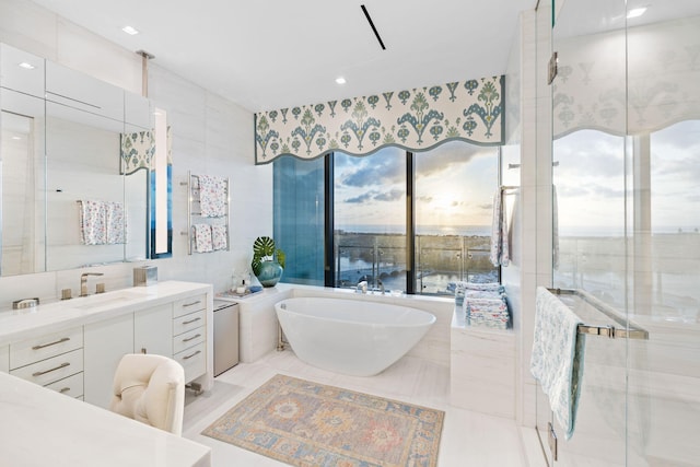 bathroom featuring tile patterned floors, vanity, a bath, and tile walls