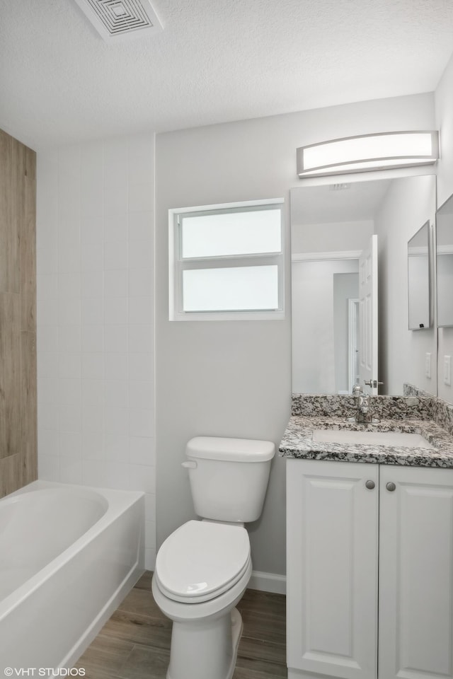 full bathroom featuring a textured ceiling, vanity, hardwood / wood-style flooring, and toilet