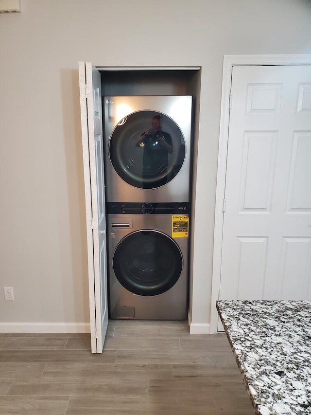 clothes washing area featuring stacked washer and dryer and hardwood / wood-style floors