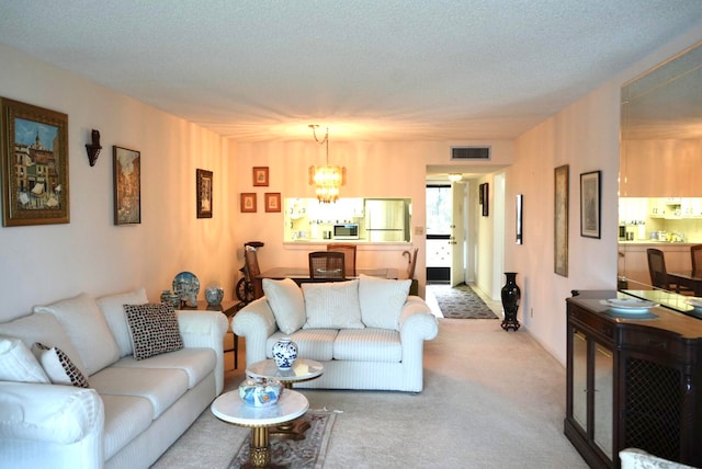 living room with carpet flooring, a textured ceiling, and an inviting chandelier