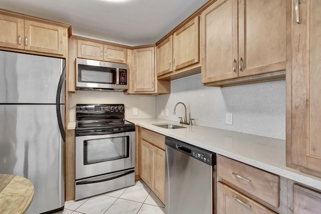 kitchen with light tile patterned floors, stainless steel appliances, light brown cabinetry, and sink