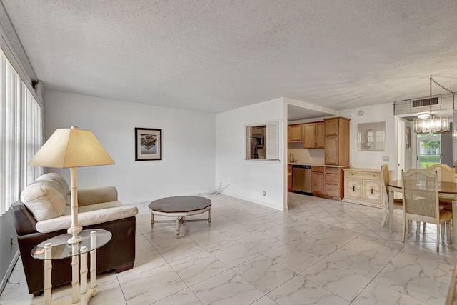 living room featuring sink, a textured ceiling, and a chandelier