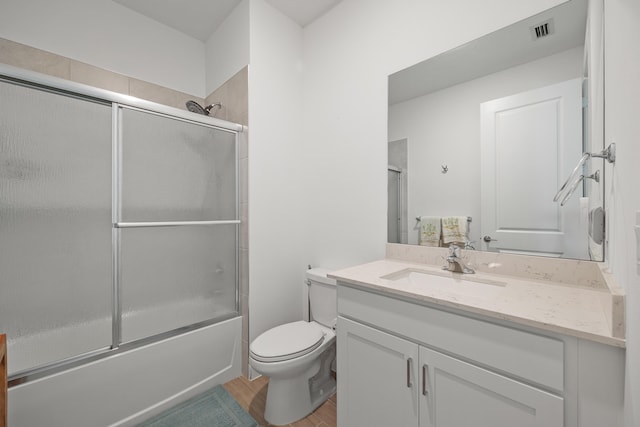 full bathroom featuring vanity, toilet, and bath / shower combo with glass door