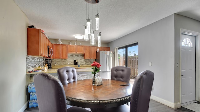 dining space with light wood-type flooring and a textured ceiling