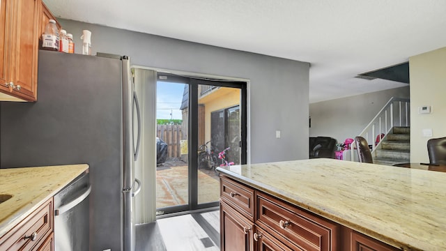 kitchen with light stone countertops, appliances with stainless steel finishes, and light wood-type flooring