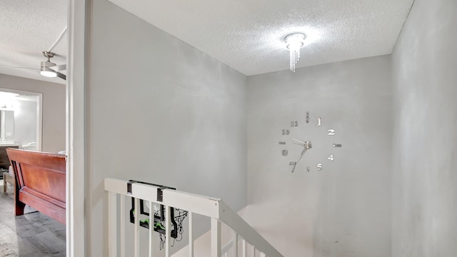 staircase with ceiling fan and a textured ceiling