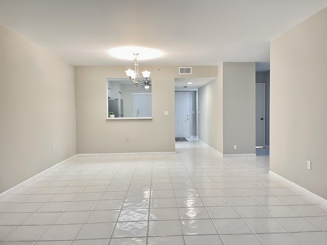 tiled empty room with an inviting chandelier