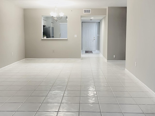 spare room featuring a notable chandelier and light tile patterned flooring