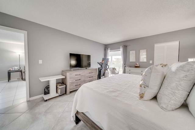 bedroom featuring a closet, a textured ceiling, and light tile floors